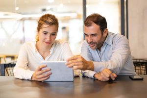 Consulente affianca un’esercente con supporto su tablet per una cassa automatica