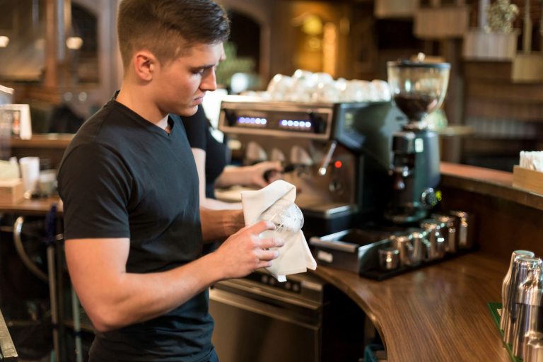Barista lavora dietro al banco durante il servizio in un bar